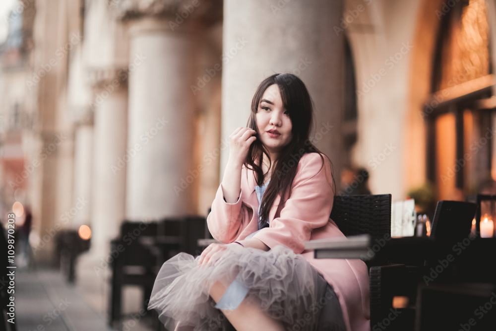 Fototapeta premium Beautiful Asian girl model in dress sitting at the old city background