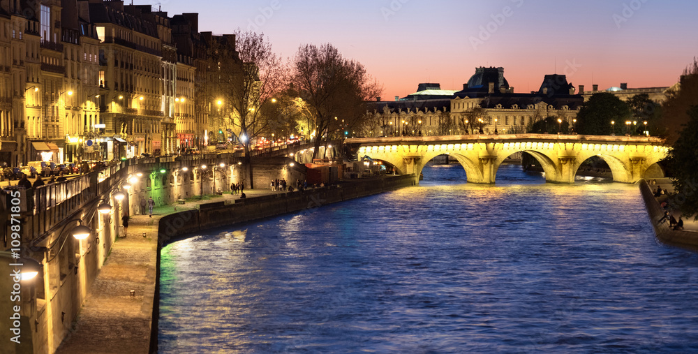 Paris, panorama along Seine river towards illuminated Pont Neuf