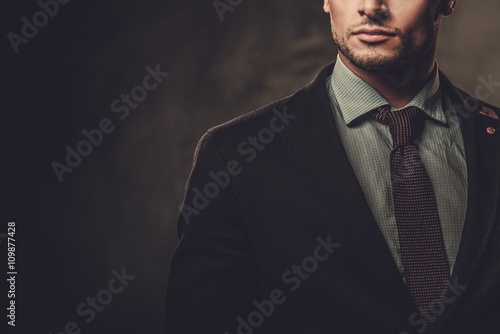 Fototapeta Serious well-dressed hispanic man posing on dark background.