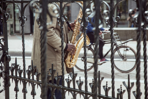 Canvas Print african street musician playing jazz on saxophone throw lattice with bicycle sil