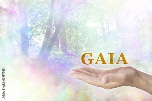 GAIA Philosophy - male hand palm up with a gold GAIA word floating above and a rainbow colored bokeh effect woodland scene behind photo