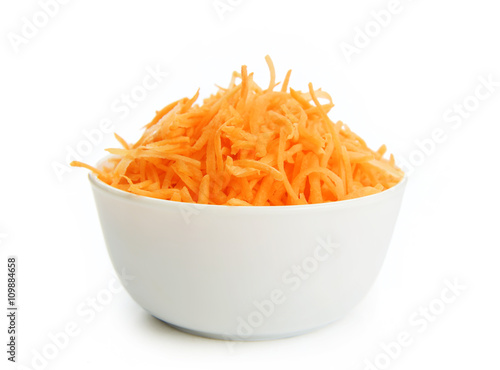 Grated carrots in a white cup on a white background