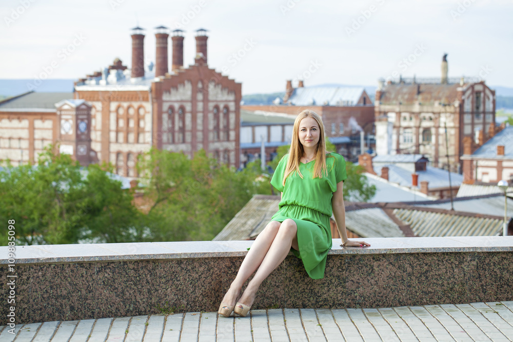 Young beautiful woman in green dress posing outdoors in sunny we