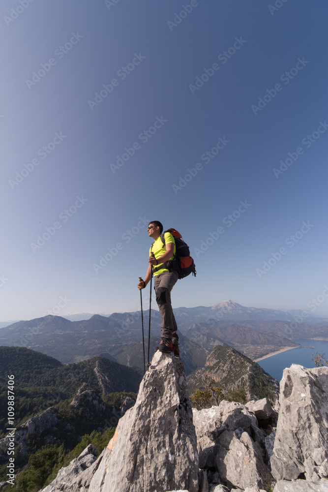 Young man with backpack on a mountain top on a sunny day.