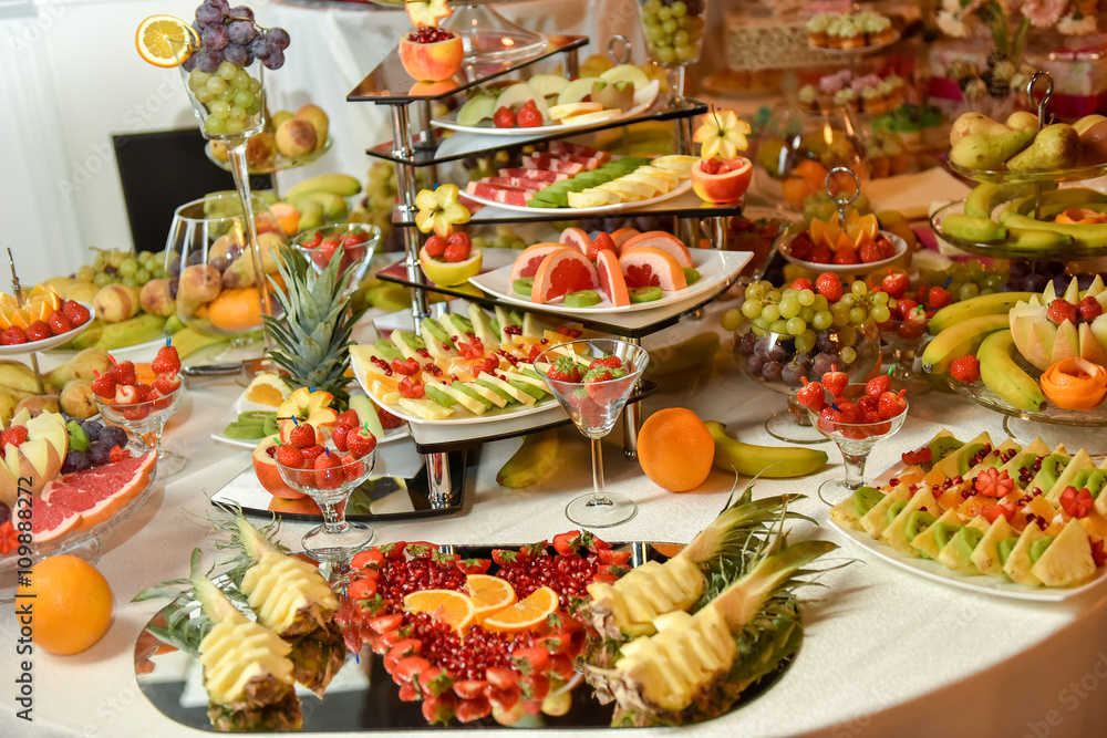 Plates with different type of fruits: grape, strawberry, pineapple, orange, pomegranate, kiwi, banana