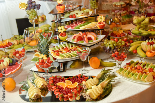 Plates with different type of fruits: grape, strawberry, pineapple, orange, pomegranate, kiwi, banana