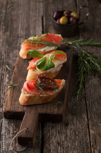 Bruschetta with smoked salmon, cheese, herbs and olives