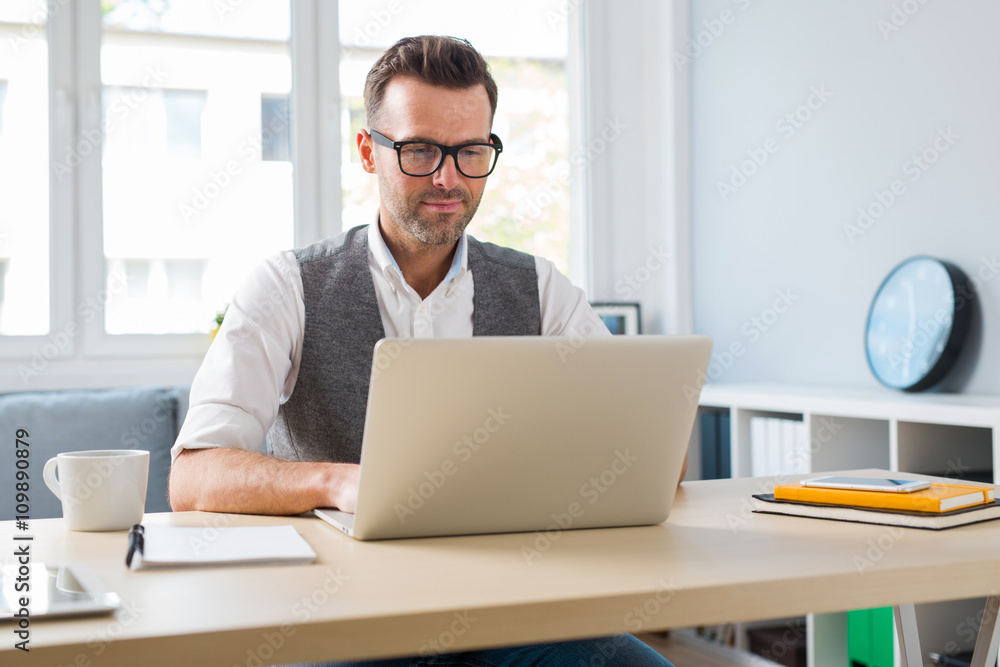 Handsome man working on laptop at office or home Handsome man working on laptop at office or home