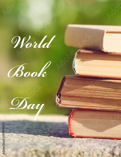 Stack of books in park on blurred background. World Book Day poster