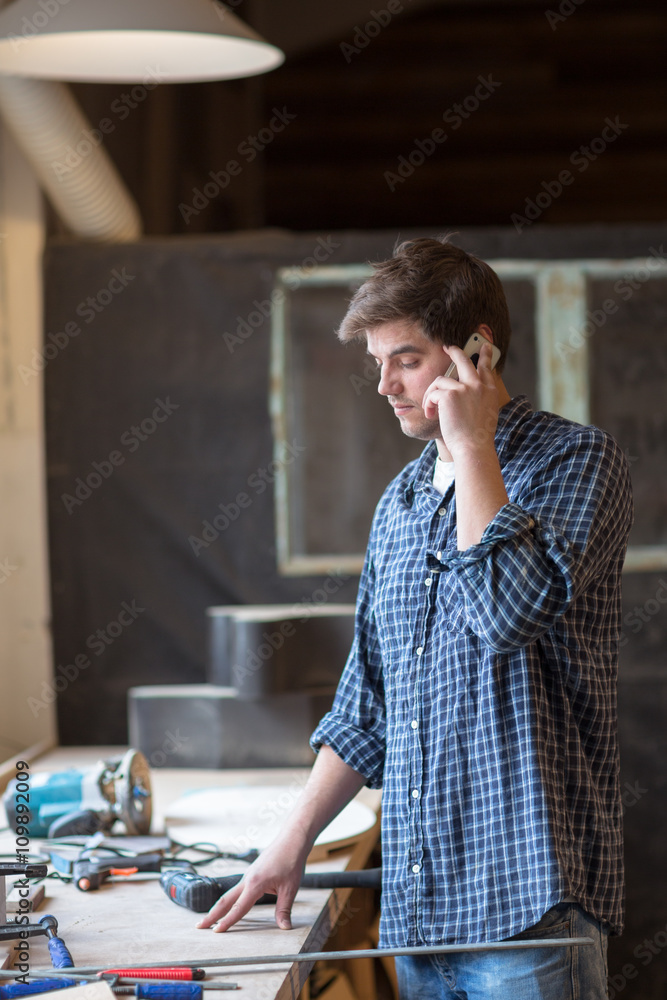 Male carpenter in carpentry shop on the phone, man at work, lif Male carpenter in carpentry shop on the phone, man at work, lif
