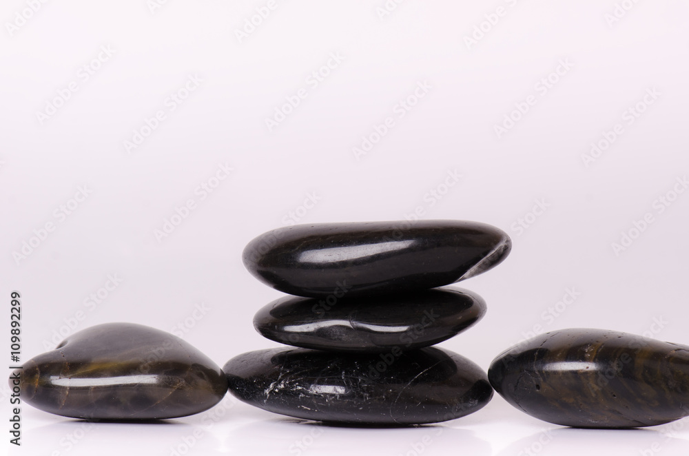 Stone treatment. Black massaging stones isolated on a white background. Hot stones. Balance. Zen like concepts. Basalt stones. Stone treatment. Black massaging stones isolated on a white background. Hot stones. Balance. Zen like concepts. Basalt stones.