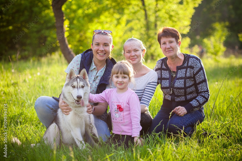 Obraz premium happy family sit in the grass with husky