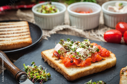 Grilled toasted bread with roasted tomatoes, feta cheese and radish sprouts.