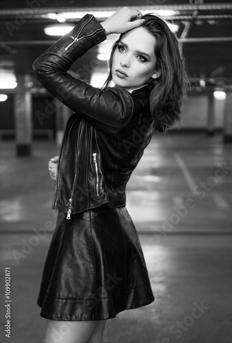 Fashionable young brunette woman posing wearing leather skir photo