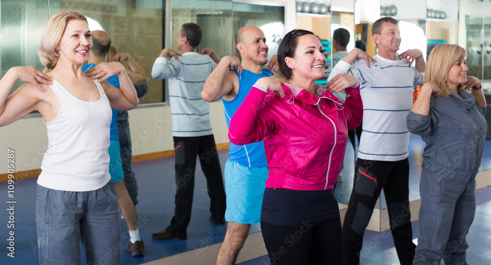 Fototapeta Grupa dorosłych wykonujących ćwiczenia aerobiku w klubie sportowym