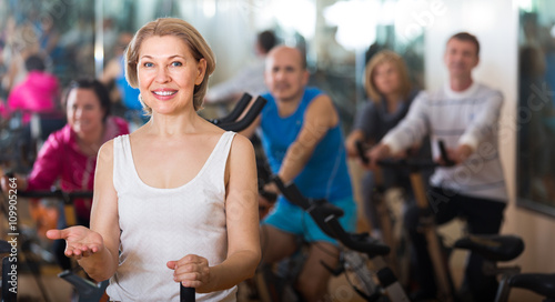 Woman on fitness cycle with people