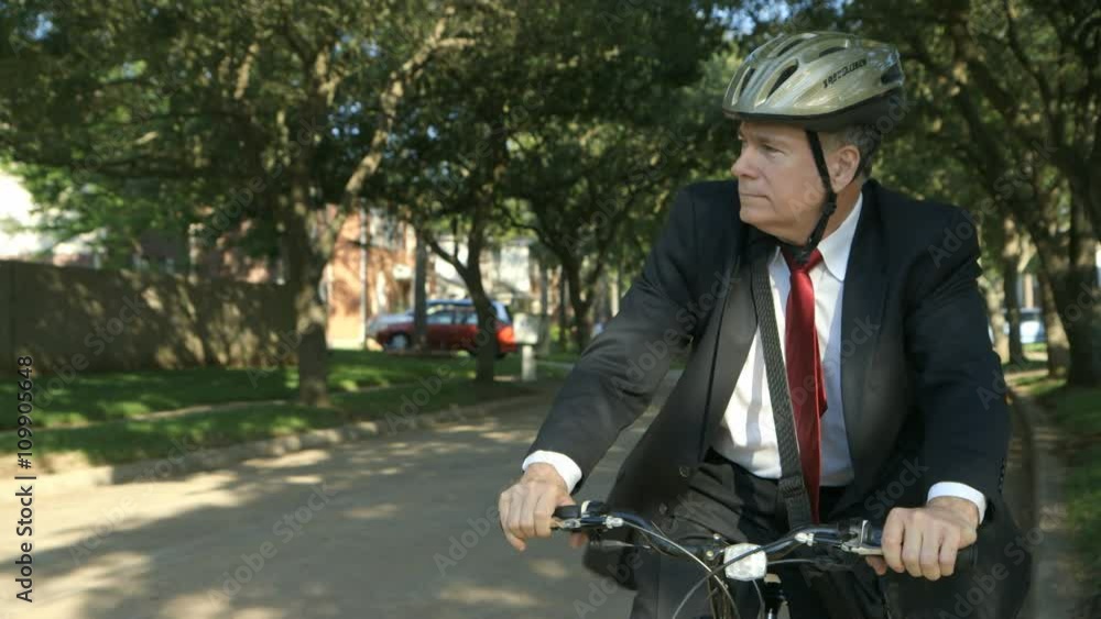A businessman using an eco-friendly mode of transportation stops his bicycle and checks for traffic. A businessman using an eco-friendly mode of transportation stops his bicycle and checks for traffic.