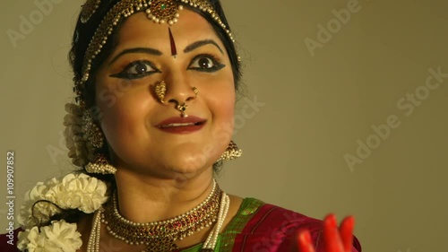 A very expressive lovely young woman using traditional mudra or hand gestures to tell a story during classical Indian dance. photo