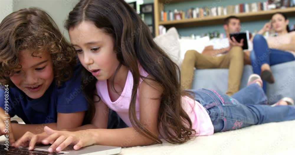 Two children are using computer while parents are using pad Two children are using computer while parents are using pad