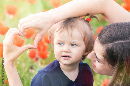 Mother with funny child outdoor at poppy flowers field photo