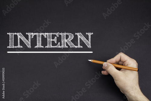 Hand with a white pencil writing: INTERN