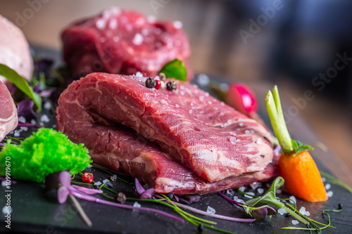 Steak.Beef steak.Meat.Portioned meat.Raw fresh meat.Sirloin steak.T-Bone steak. Flank steak. Duck breast. Vegetable decoration. Portioned meat prepared for processing in a restaurant or hotel kitchen.