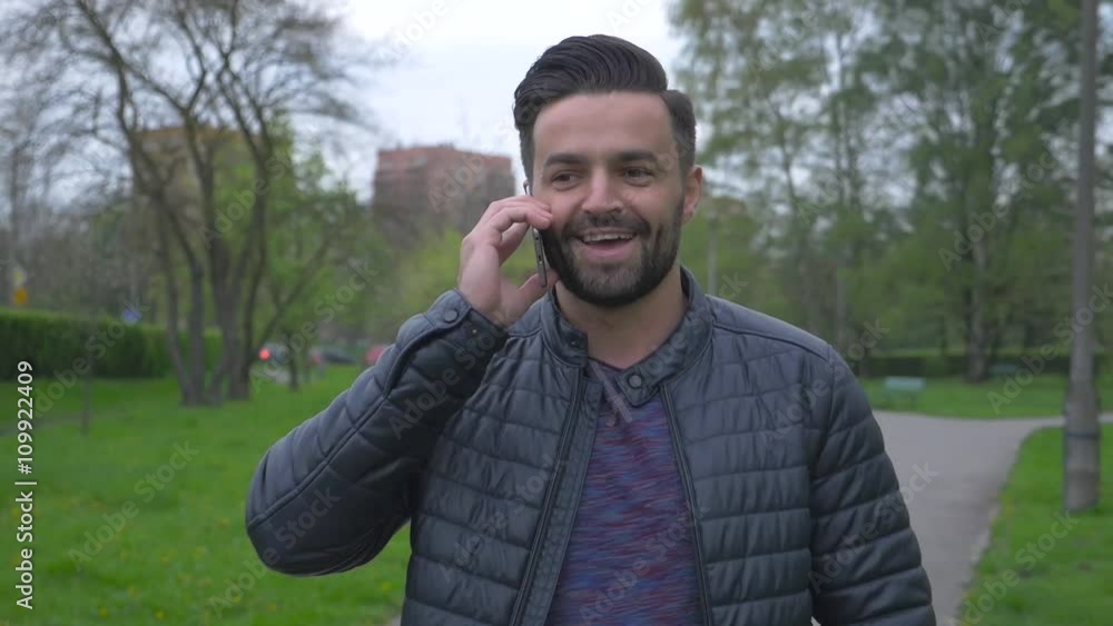 Young man walking in the park and talking on the phone.
Young man walking in the park and talking on the phone.