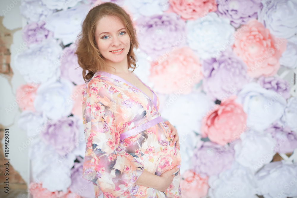 pregnant woman in pink on a background of flowers interior pregnant woman in pink on a background of flowers interior