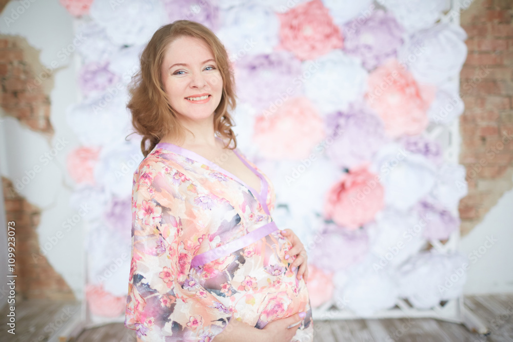 pregnant woman in pink on a background of flowers interior pregnant woman in pink on a background of flowers interior