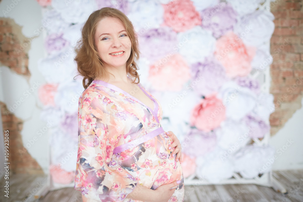 pregnant woman in pink on a background of flowers interior pregnant woman in pink on a background of flowers interior