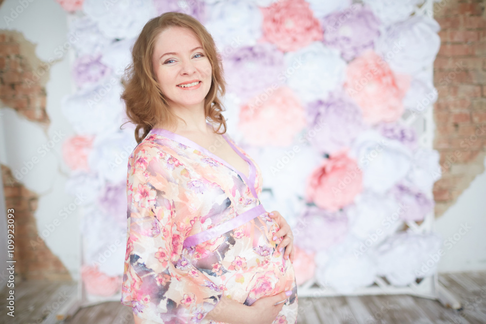 pregnant woman in pink on a background of flowers interior pregnant woman in pink on a background of flowers interior