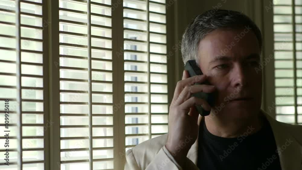 A man standing next to a window having a heated cell phone conversation. A man standing next to a window having a heated cell phone conversation.