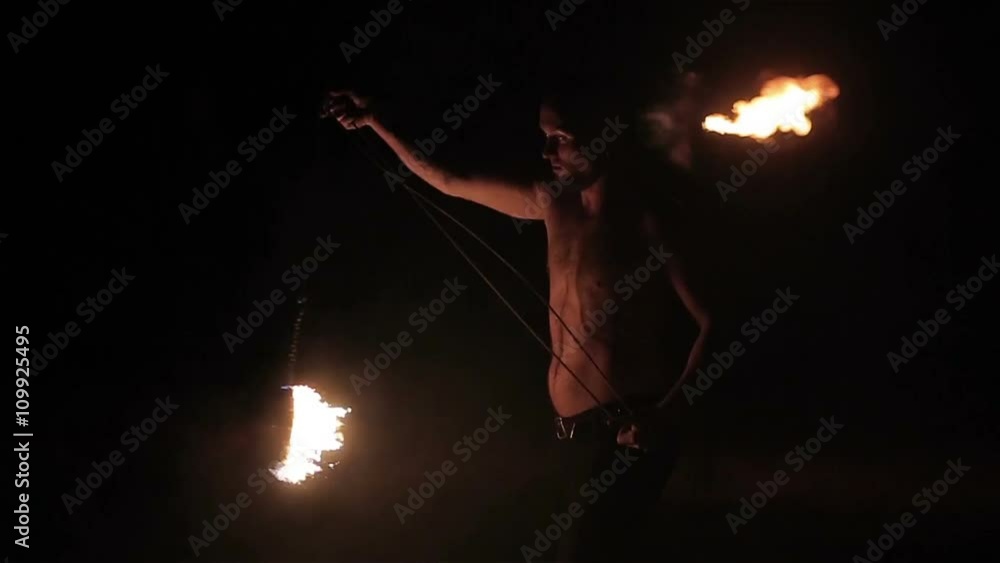Fire show performance. Male fire performer spinning burning fire rope