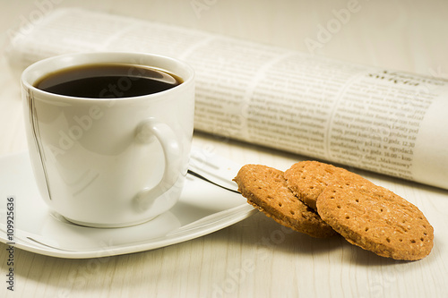 Coffee cup with cookies and newspaper