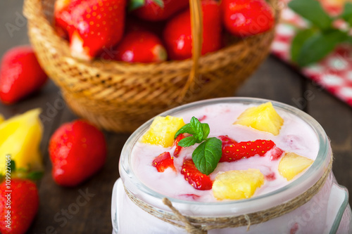   Bowl of strawberry and pineapple flavored yogurt  over a wooden table