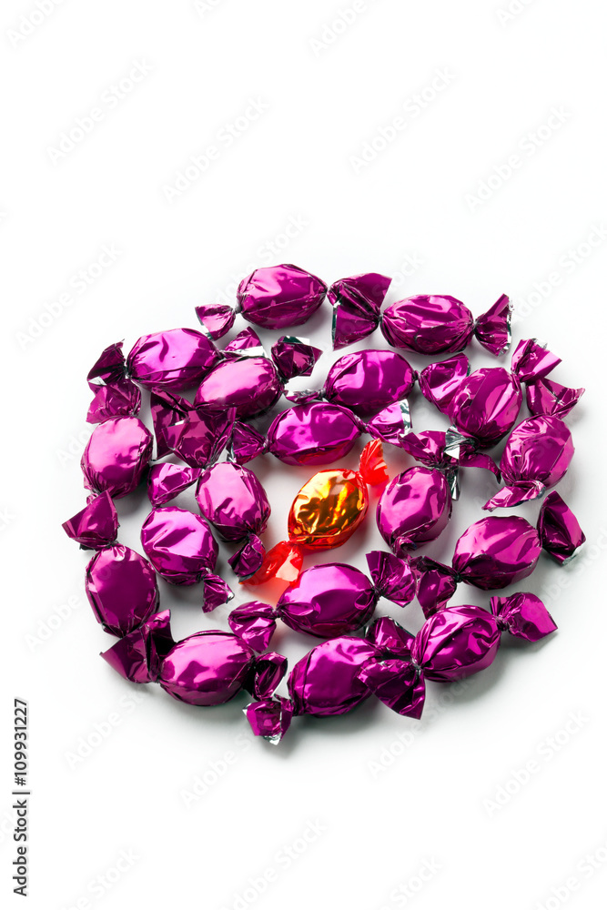 top view of a golden candy arranged between shiny purple hard candies. top view of a golden candy arranged between shiny purple hard candies.