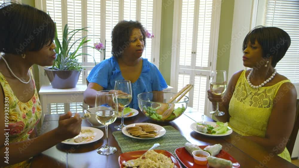 Lunching together in a home three lovely African American women enjoy the company of one another. Lunching together in a home three lovely African American women enjoy the company of one another.