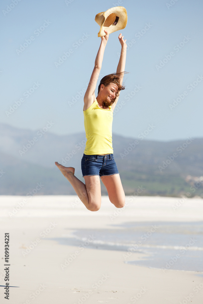 Excited young woman jumping on the beach Excited young woman jumping on the beach