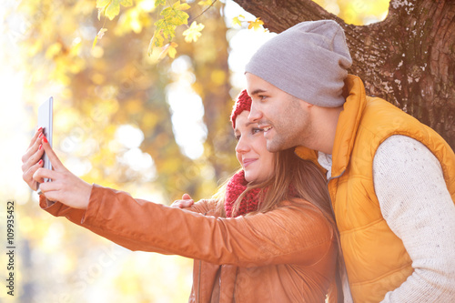 Portrait of young couple in park enjoying together and making selfie.