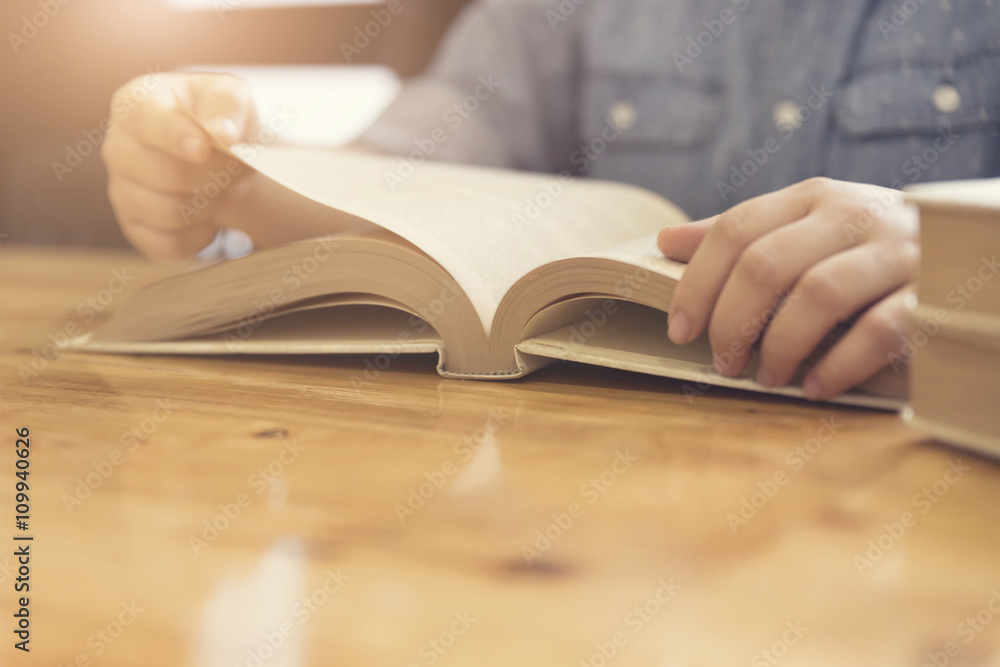woman's hand reading book on wooden table woman's hand reading book on wooden table