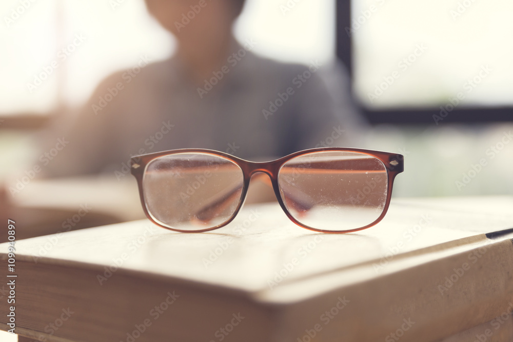 eyeglasses with woman reading book in room
