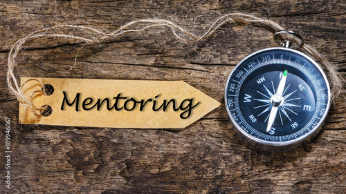 MENTORING word - business tips handwriting on label with compass