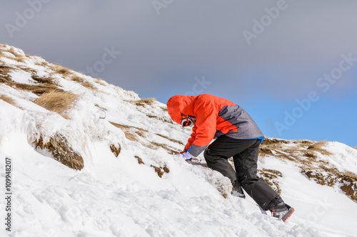 Boy climbing on mountain in wintertime. Cute little kid boy in c