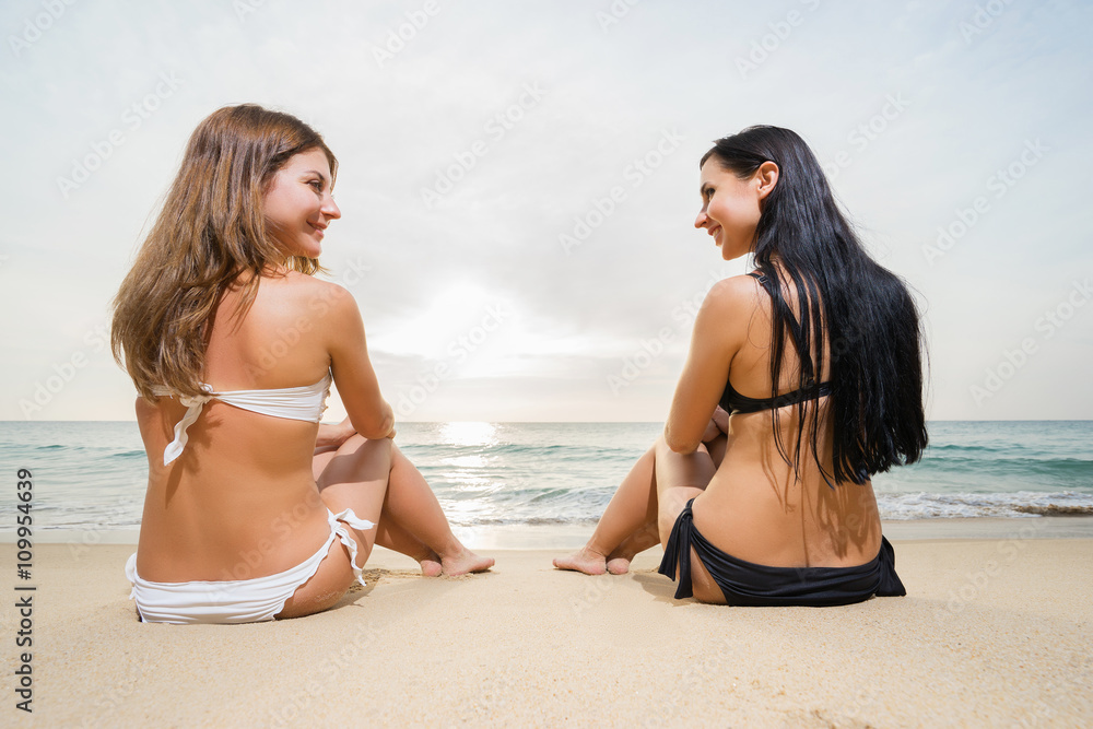 Two happy and smiling women sitting on the beach. Two happy and smiling women sitting on the beach.