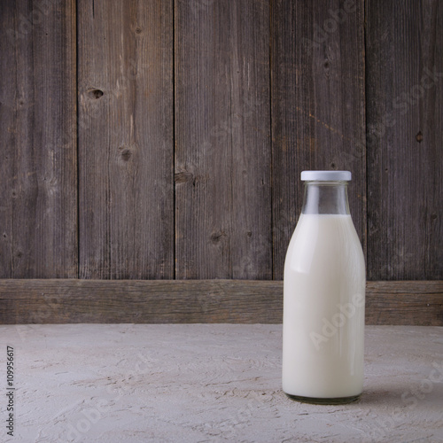 Fresh milk in glass bottle on wooden background