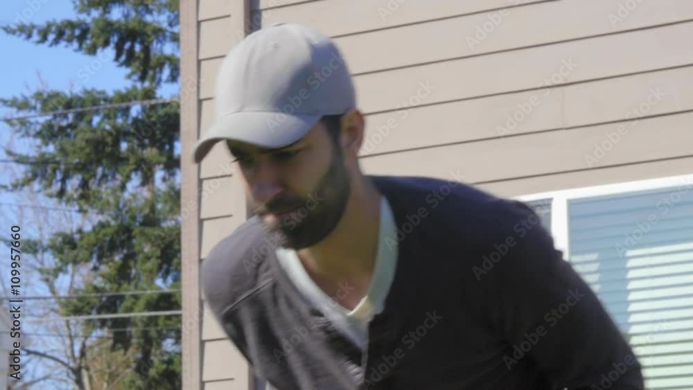 Attractive Mediterranean Man in baseball cap and beard mows a backyard lawn with a push mower in close up Attractive Mediterranean Man in baseball cap and beard mows a backyard lawn with a push mower in close up