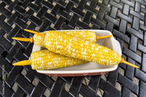 boiled corn cob on white plate closeup photo