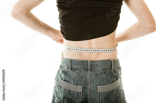 Rear view of boy measuring waist with tape measure