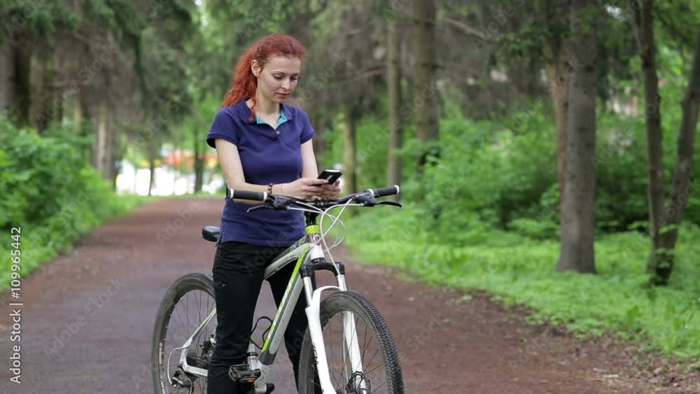 Girl sitting on the bike and texting on smartphone Girl sitting on the bike and texting on smartphone