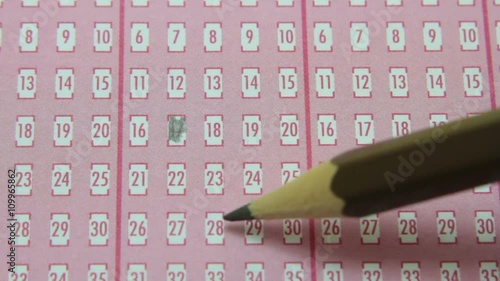 Pencil filling in numbered squares on lottery game piece. photo
